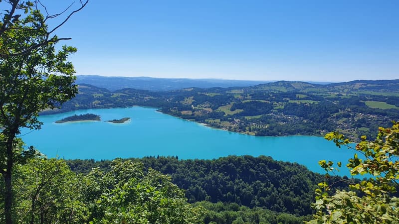 Le lac d’Aiguebelette et une île vus entre les arbres, depuis un col