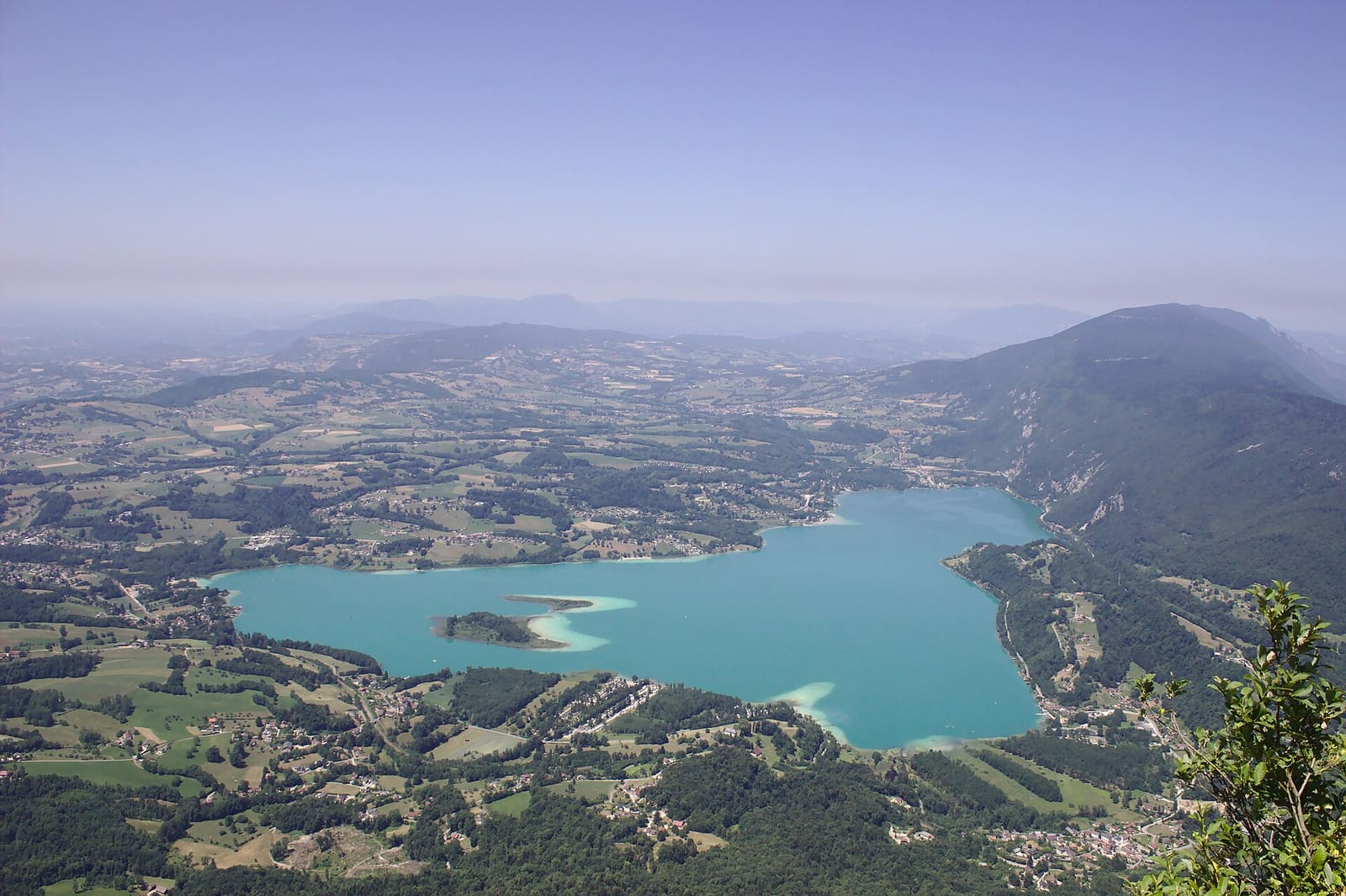 Le lac d’Aiguebelette turquoise et ses îles vus d’un sommet, la campagne autour