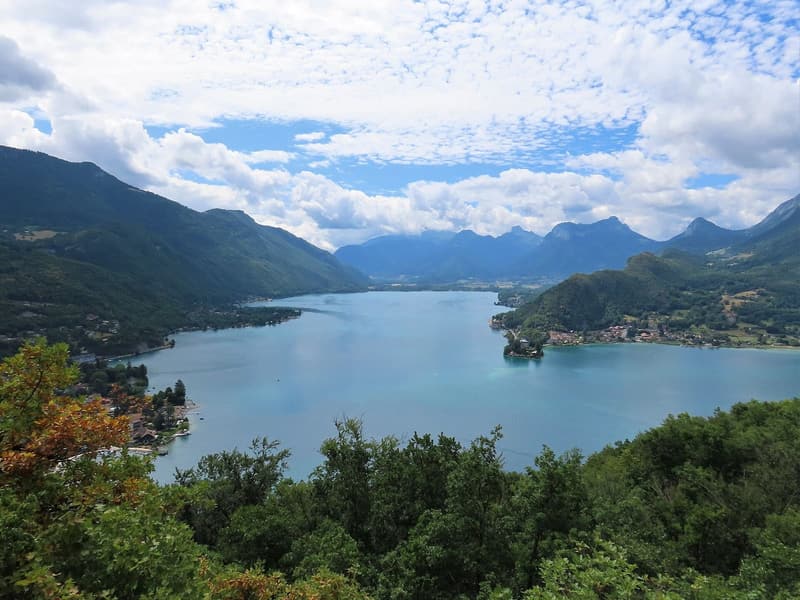 Le Petit Lac d’Annecy vu d’un promontoire boisé, montagnes en arrière-plan
