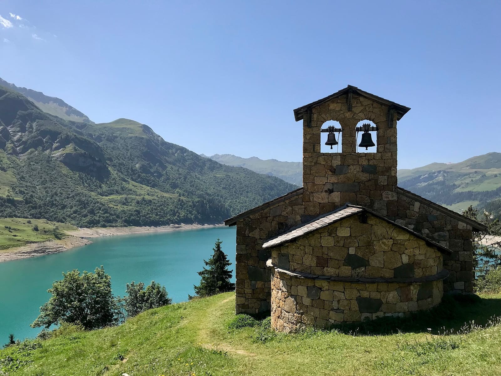 La petite chapelle de pierre de Roselend sur l’herbe, le lac derrière